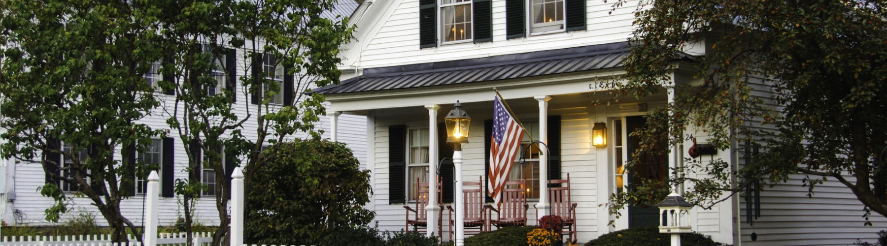 One story house with white picket fence and flag